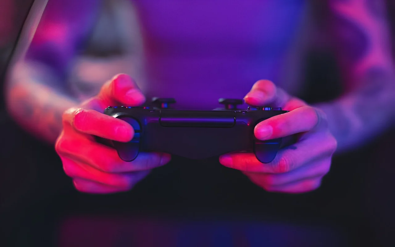 A man holding a joy stick in purple lighting